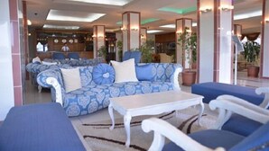 A lobby with patterned sofas, a white coffee table, and potted plants. - Grand Hotel Tesk (Ordu)