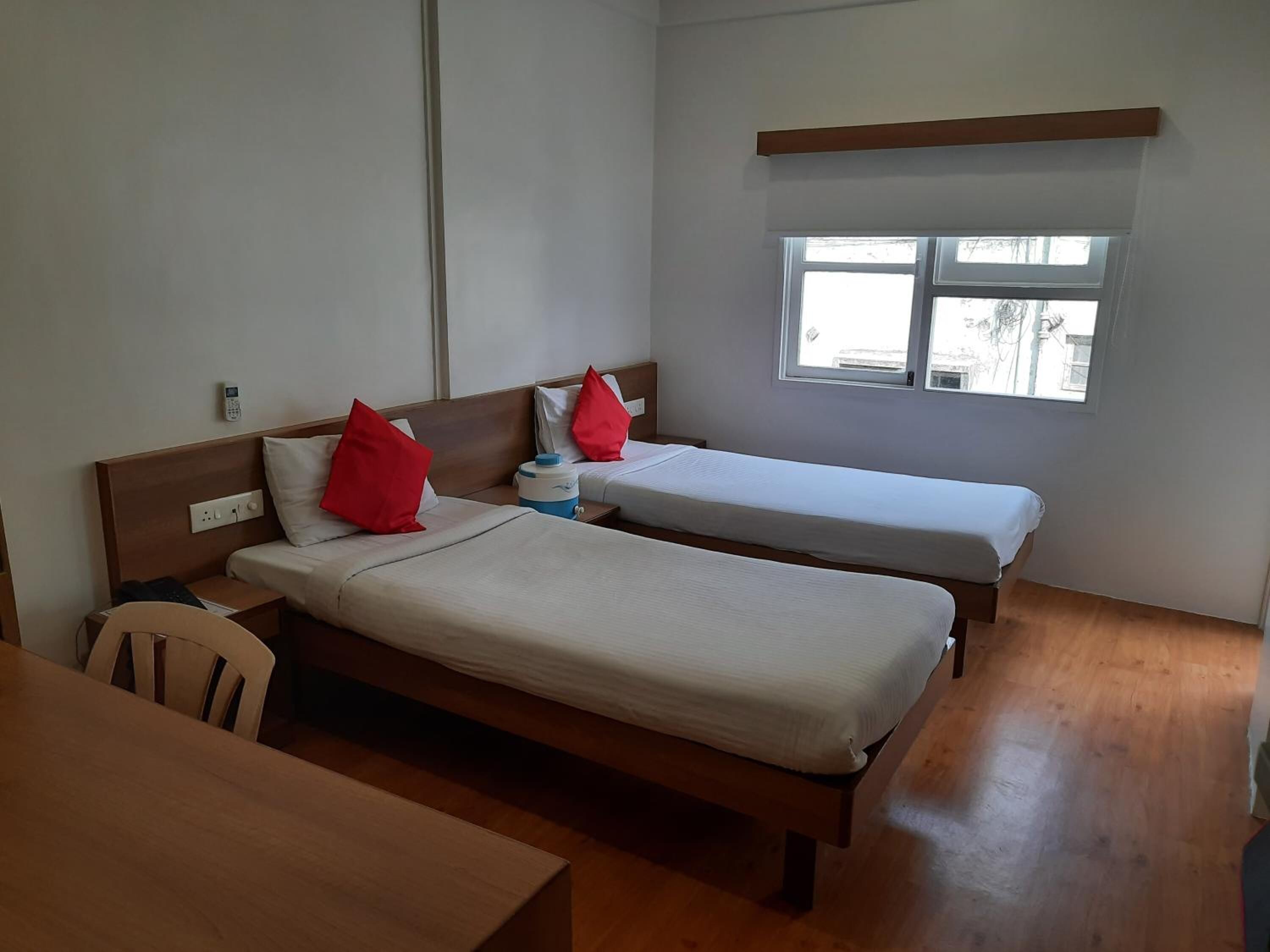 A room with two single beds, a small table, and a window.