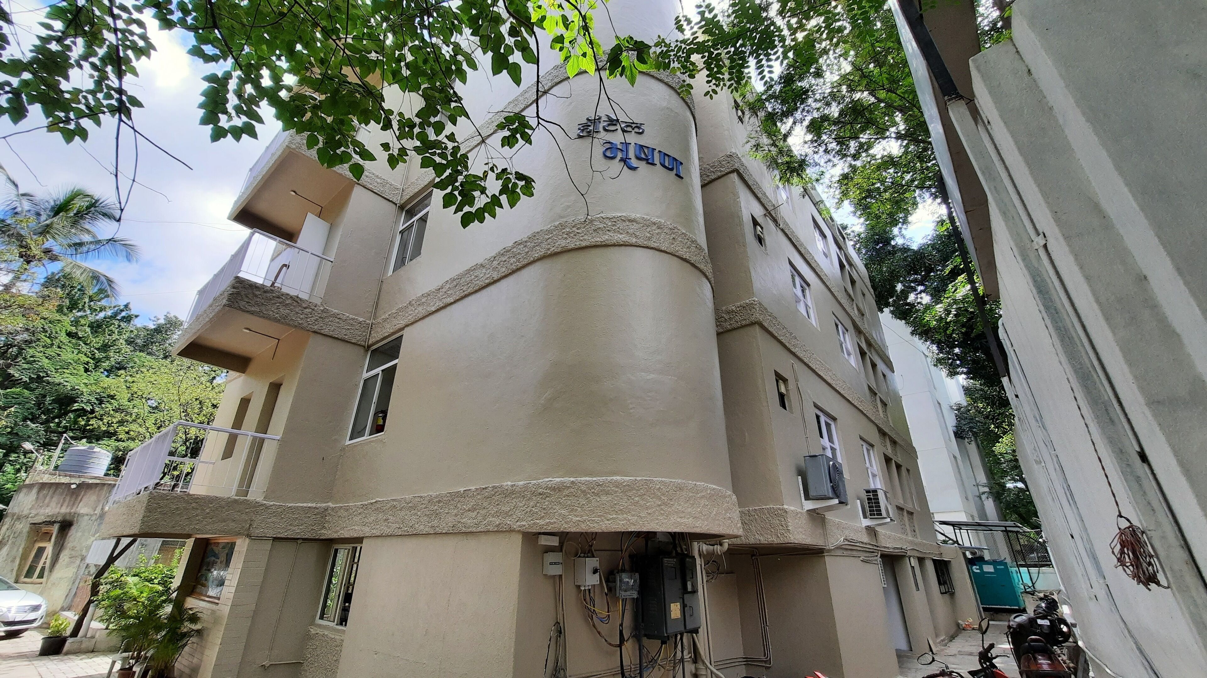 Un edificio a più piani con una facciata curva distintiva, un estintore in evidenza e una motocicletta parcheggiata all'esterno.