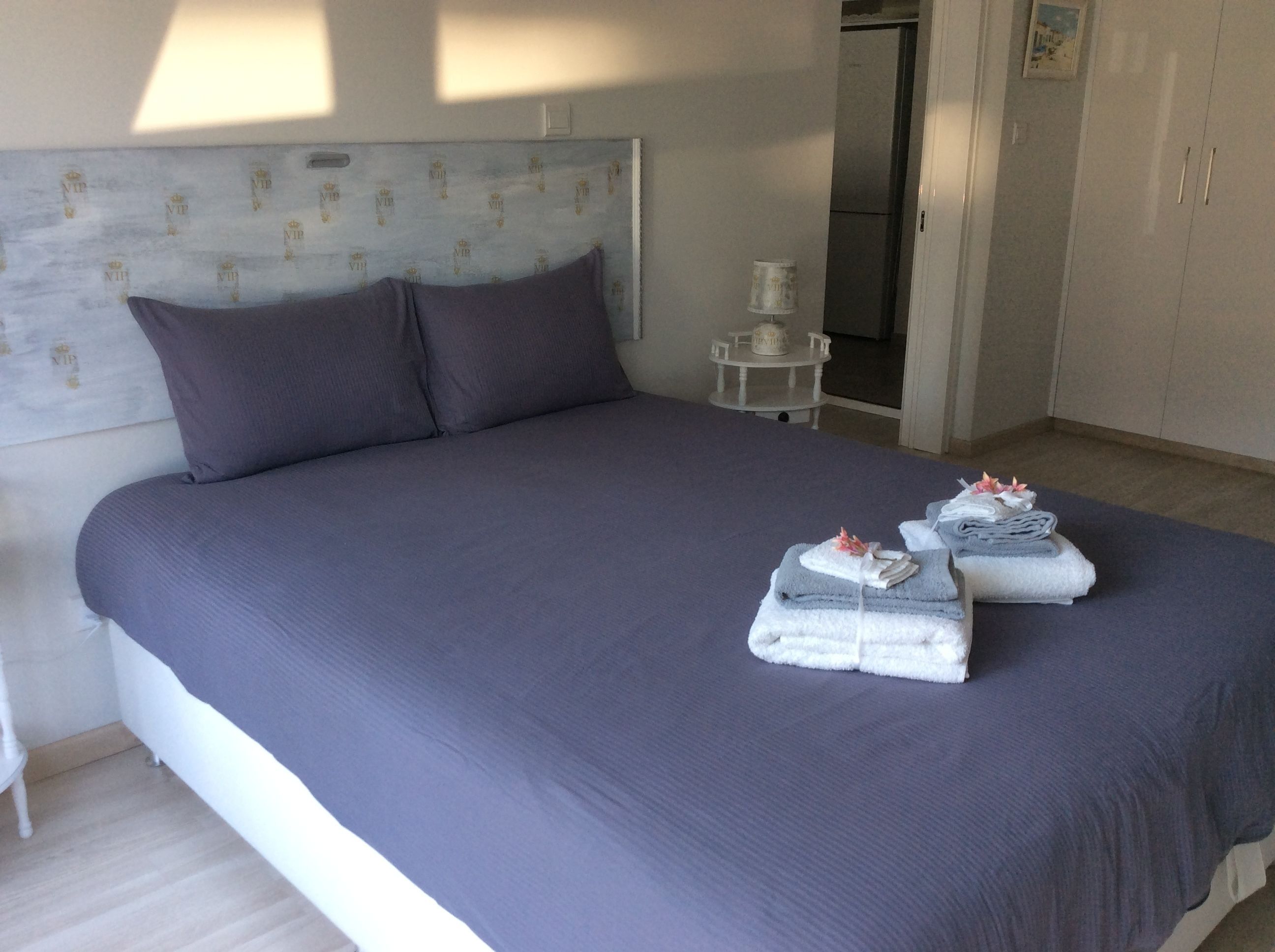 Un lit bien fait, avec une tête de lit, des oreillers et des serviettes posés sur le lit.