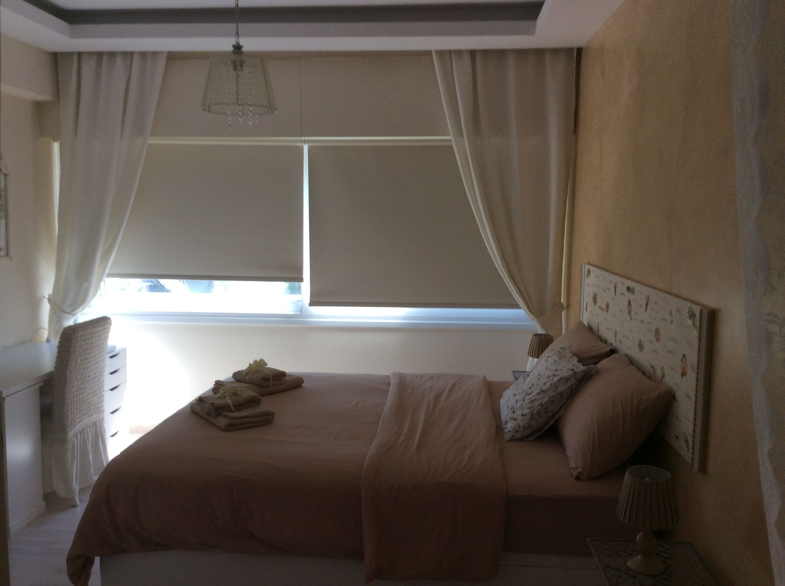 A bedroom with a bed, curtains, a window, a lamp, and a headboard.