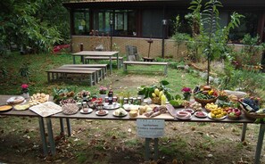 An outdoor market with various food items displayed on tables, surrounded by greenery and a building in the background. - Agriturismo Costiera Amalfitana (Tramonti)