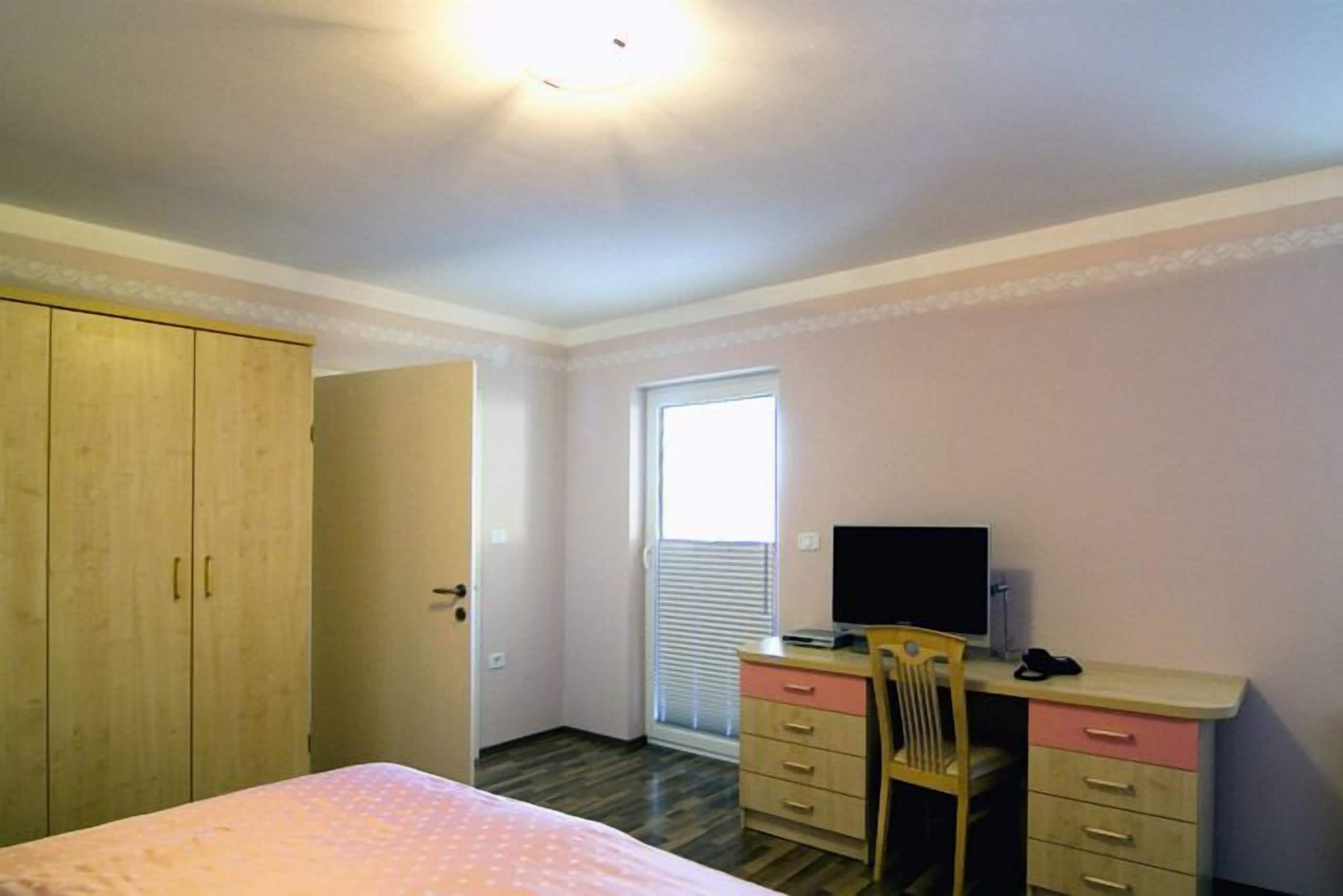 Une chambre à coucher avec un lit, un bureau et une chaise, une armoire et une fenêtre.