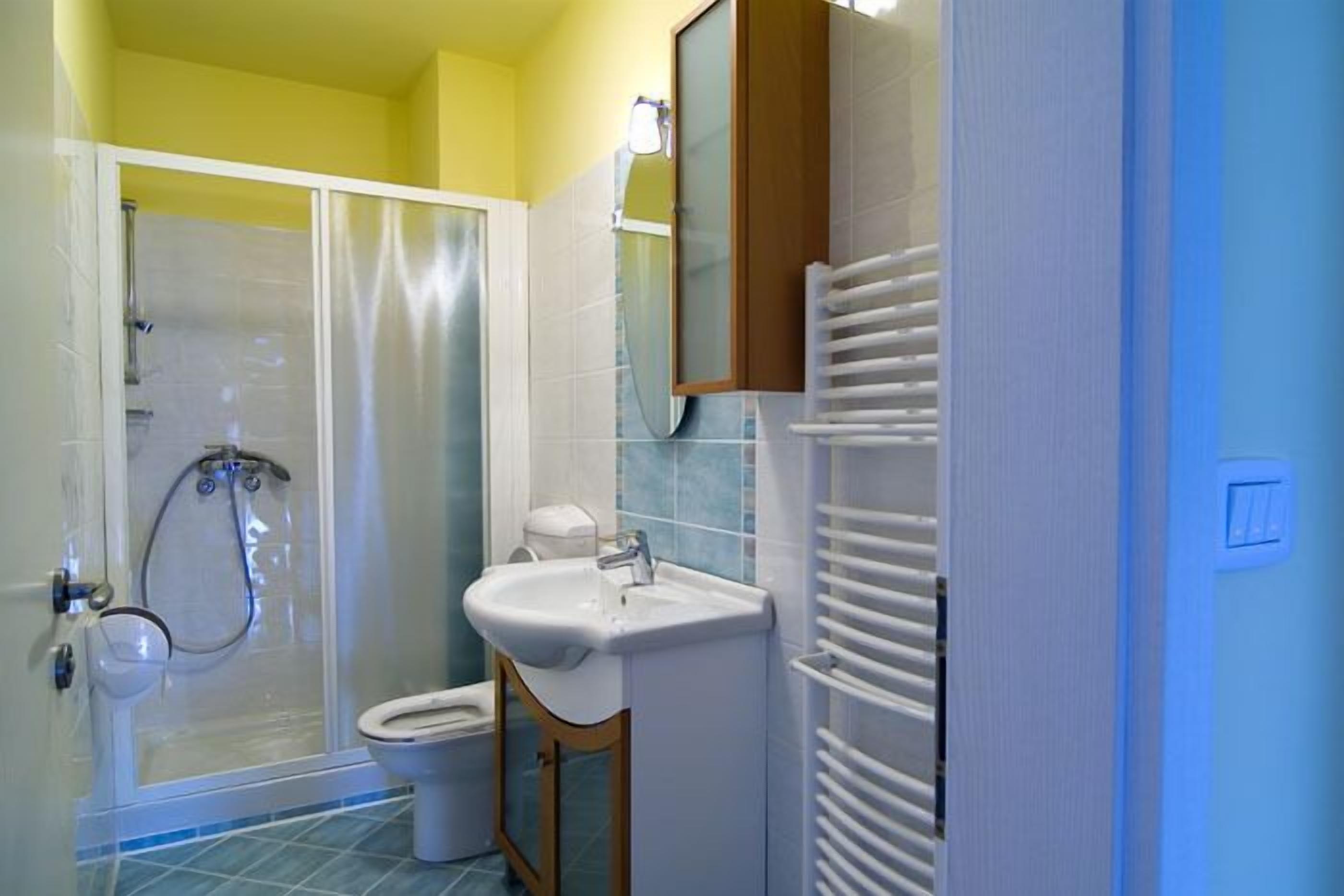 A bathroom with a shower, toilet, sink, and a towel rack.