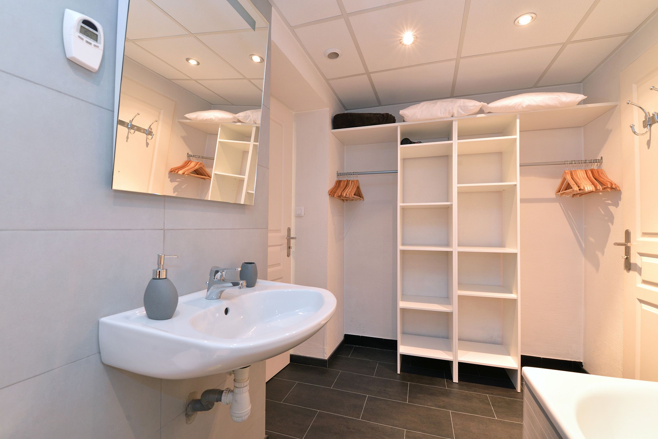 Ein modernes Badezimmer mit Waschbecken, Spiegel und integrierten Regalen.