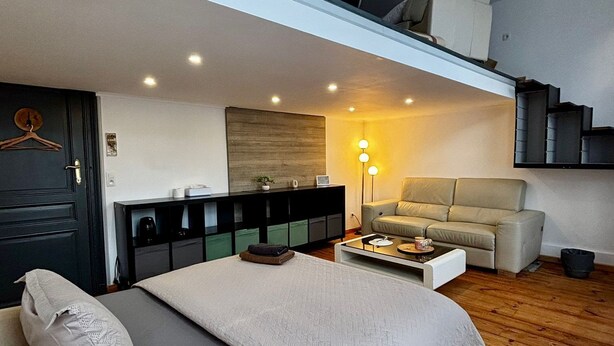 A modern bedroom with a large bed, a sofa, a coffee table, and a staircase leading to an upper level. - Budget Room Brussels (Brussels)