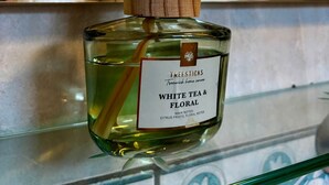 A bottle of Treesticks White Tea & Floral with two wooden sticks, placed on a glass shelf in a kitchen setting. - Budget Room Brussels (Brussels)