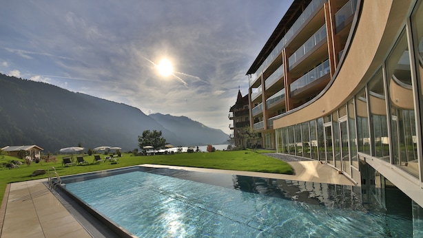 Una piscina con vistas a montañas y un edificio con balcones.