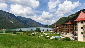 Un hotel con piscina, rodeado de montañas y un lago.