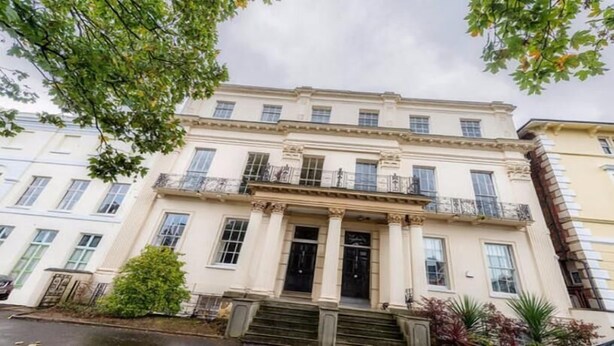 Un immeuble à étages, de style architectural classique, avec une entrée centrale ornée de colonnes, des balcons et une façade symétrique.