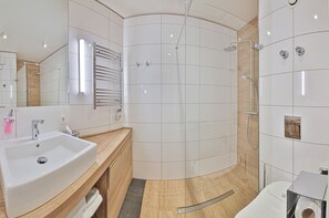 Uma casa de banho moderna com uma grande pia, um espelho, um porta-toalhas e zona de duche.