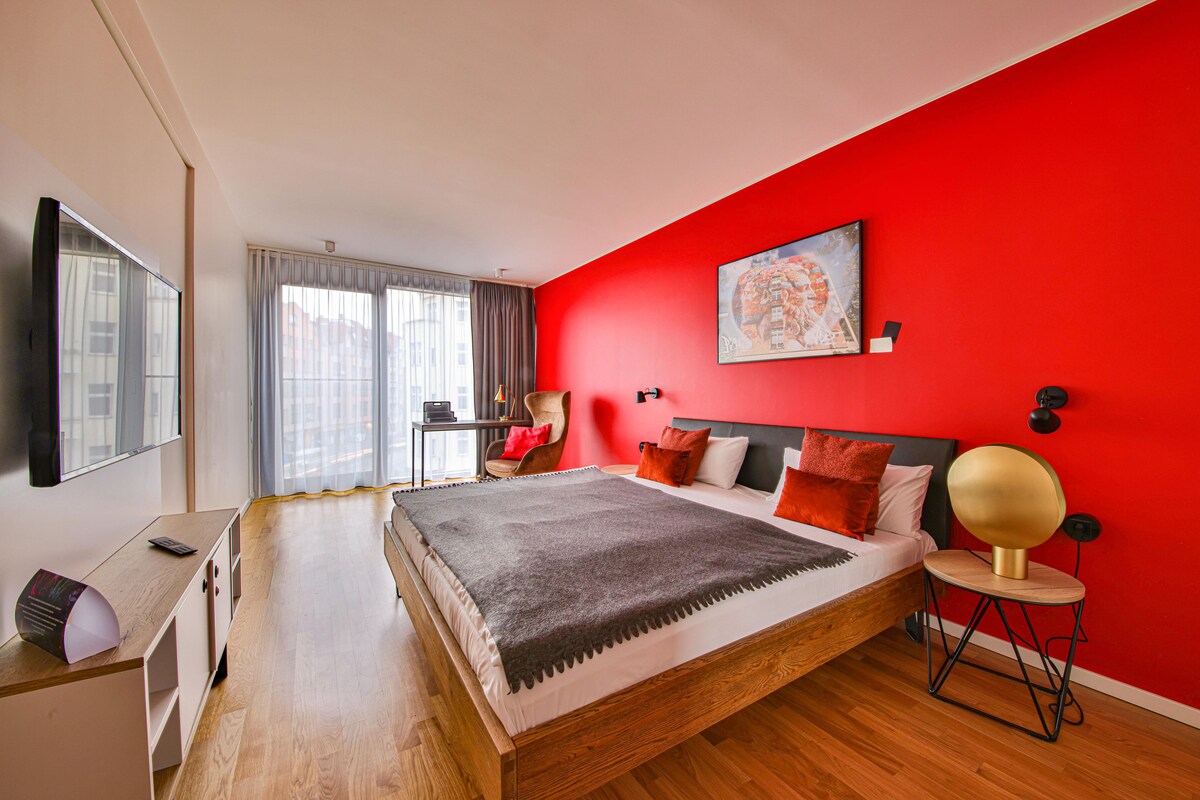 Een moderne slaapkamer met een groot bed, een bureau en een stoel.