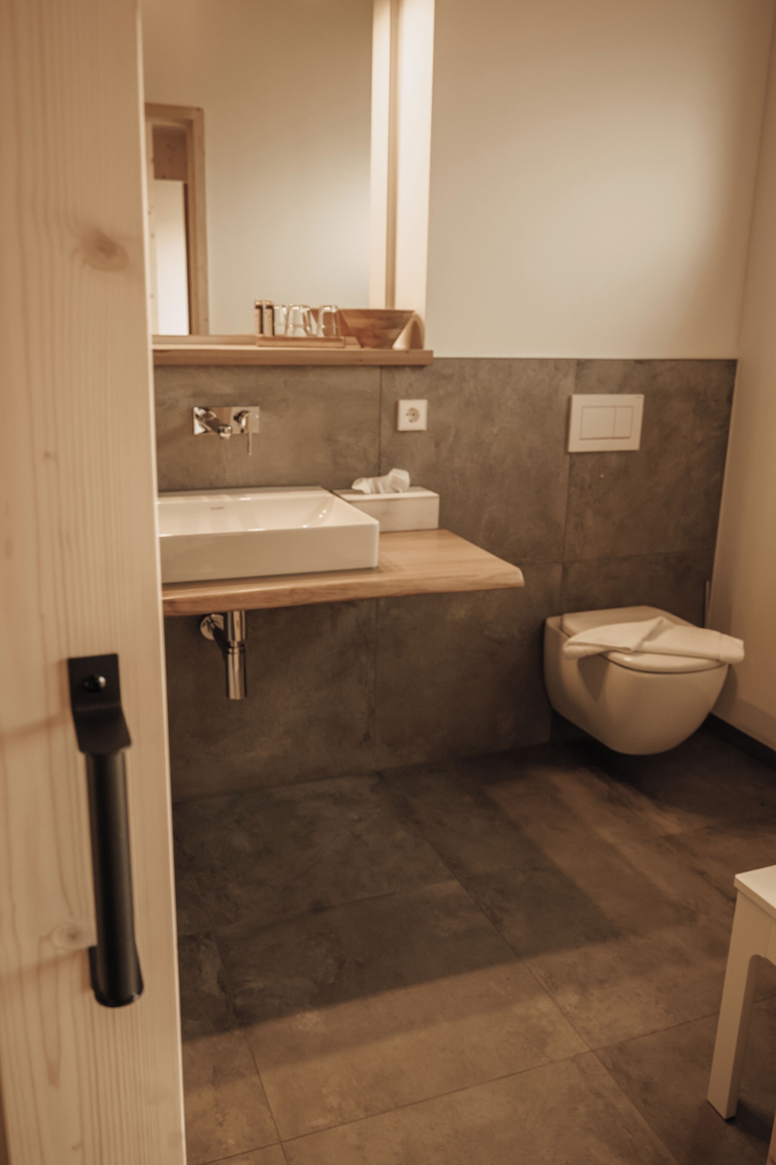 Un baño moderno con tocador de madera, lavamanos blanco y un inodoro.