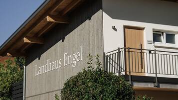 A building with the sign "Landhaus Engel" on its facade, featuring a modern architectural style with a wooden roof structure and a balcony.