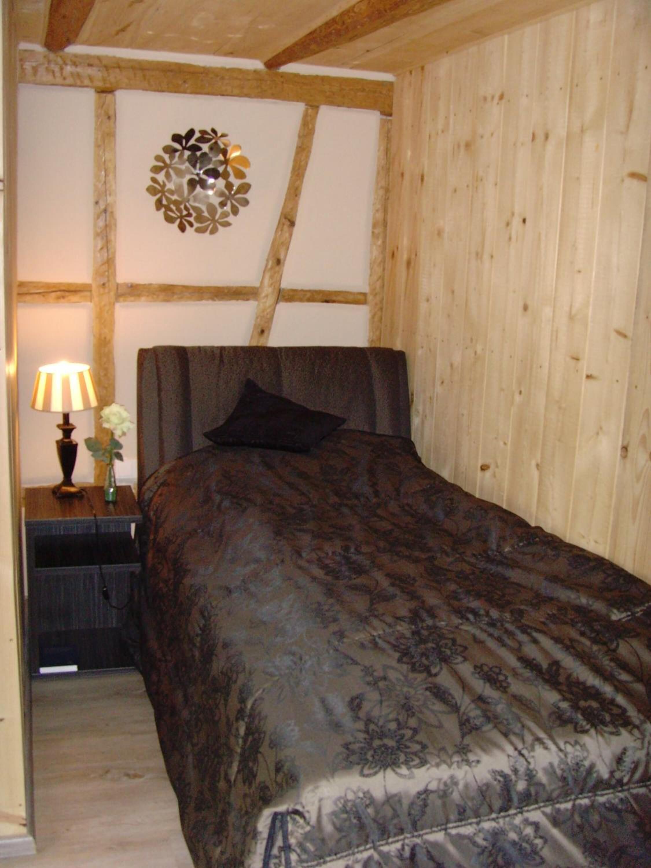 Une chambre à coucher comprenant un lit, une table de chevet, une lampe et un élément décoratif mural.