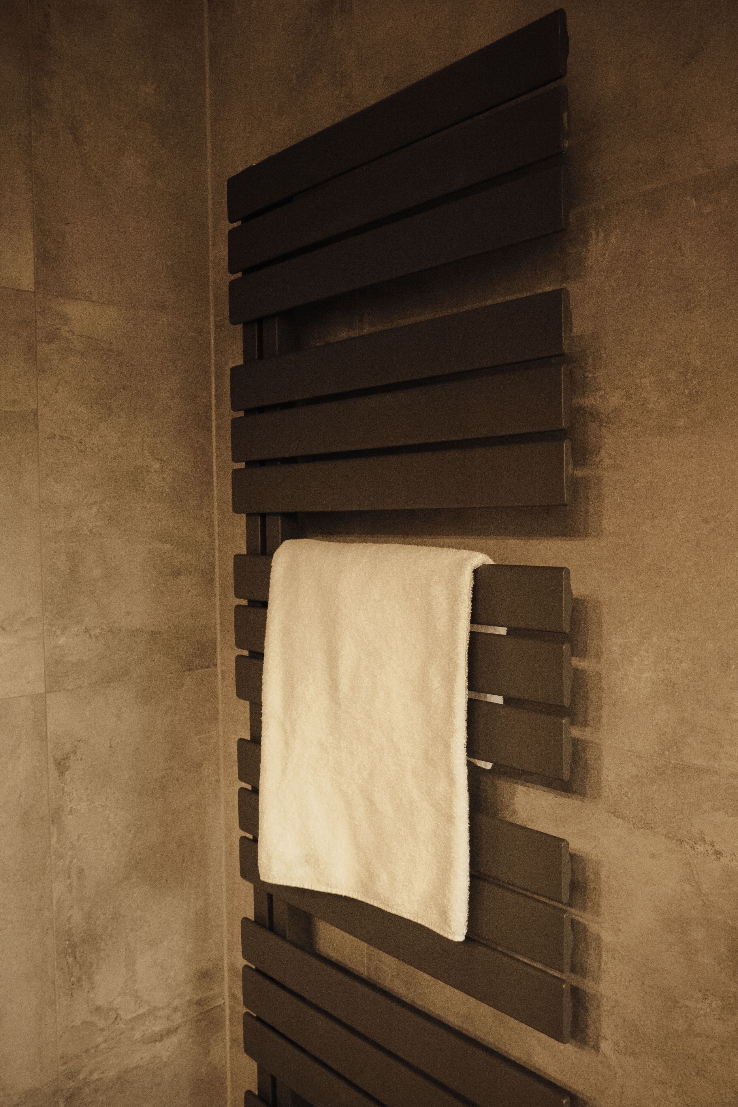 A towel hanging on a wall-mounted rack with a textured wall in the background.