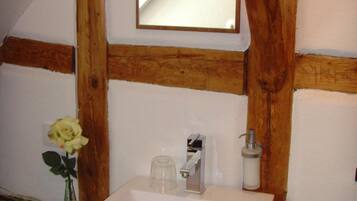 Ein Badezimmer mit weißem Waschbecken, einem Spiegel und Holzbalken.
