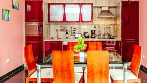 A modern kitchen with red cabinets, a glass dining table, and four chairs. - Exclusive 3 bedrooms split level sea-views apartment overlooking Bigova Bay (Bigova)