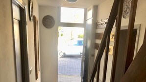 Ein Korridor mit Holzboden, einer Tür links und einer Treppe rechts.