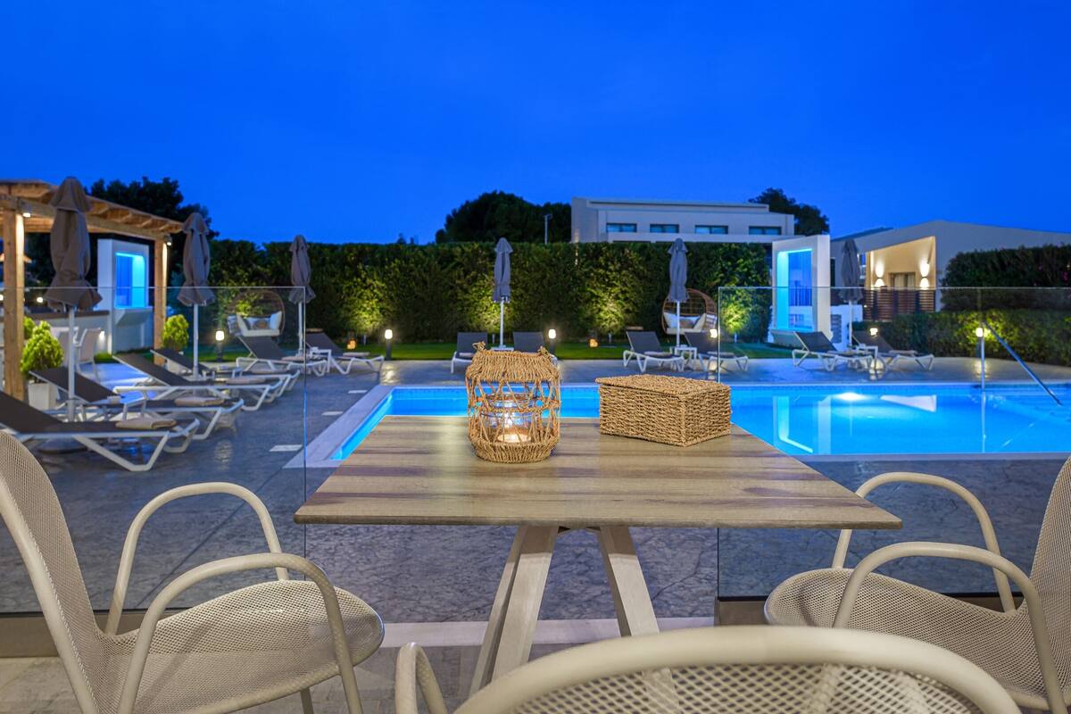 A poolside area with lounge chairs, a table with a woven basket, and a modern building in the background.