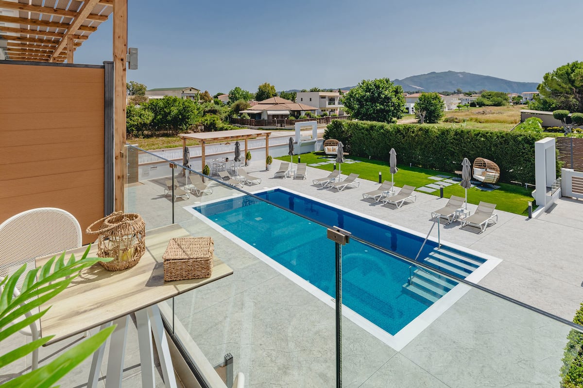 A modern outdoor swimming pool with lounge chairs and a pergola.