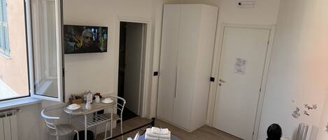 A hotel room with a bed, a small table with chairs, a TV, and a wardrobe.