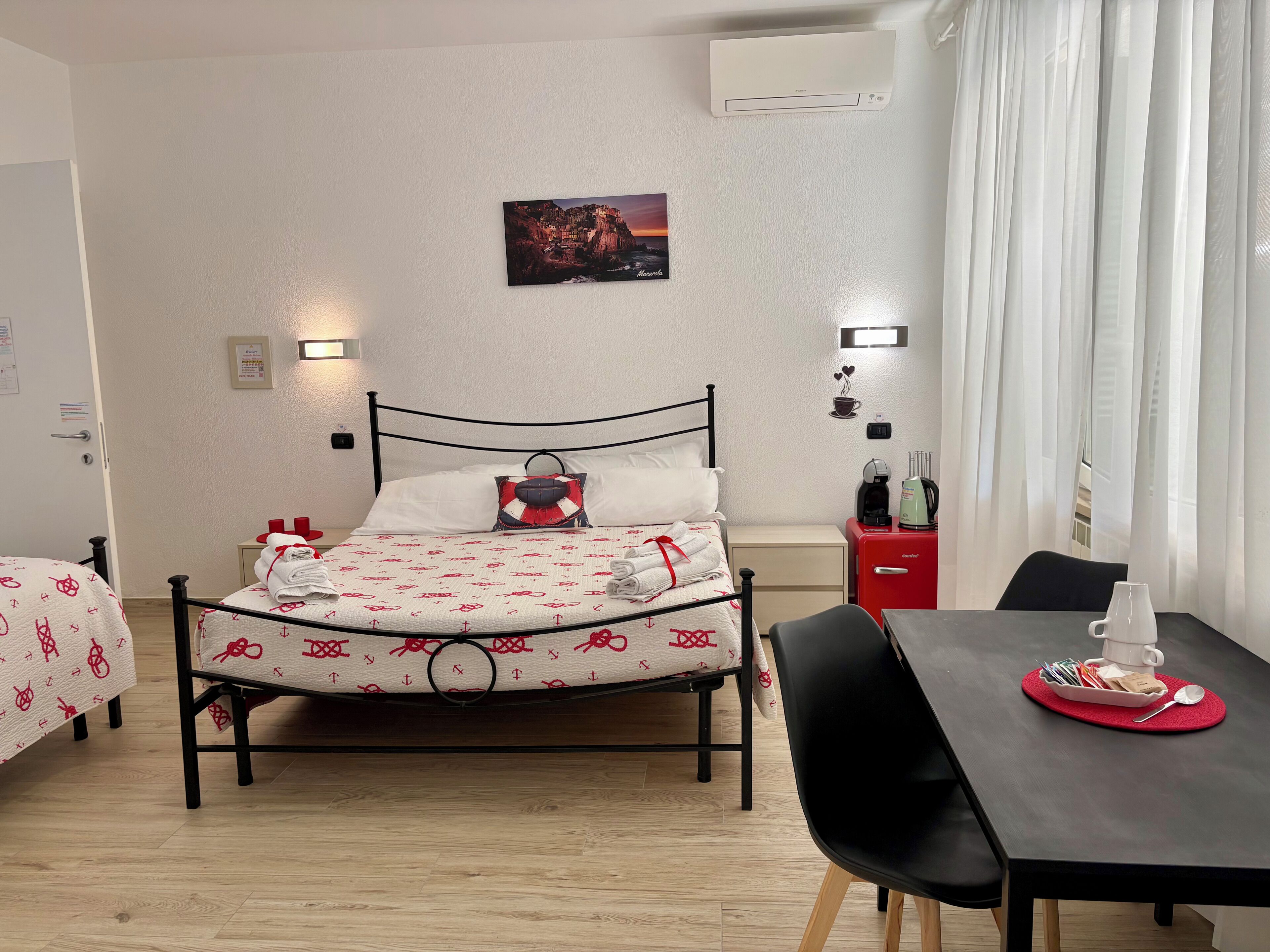 A neatly arranged hotel room with a bed, bedside table, chair, and a small table with a coffee maker.