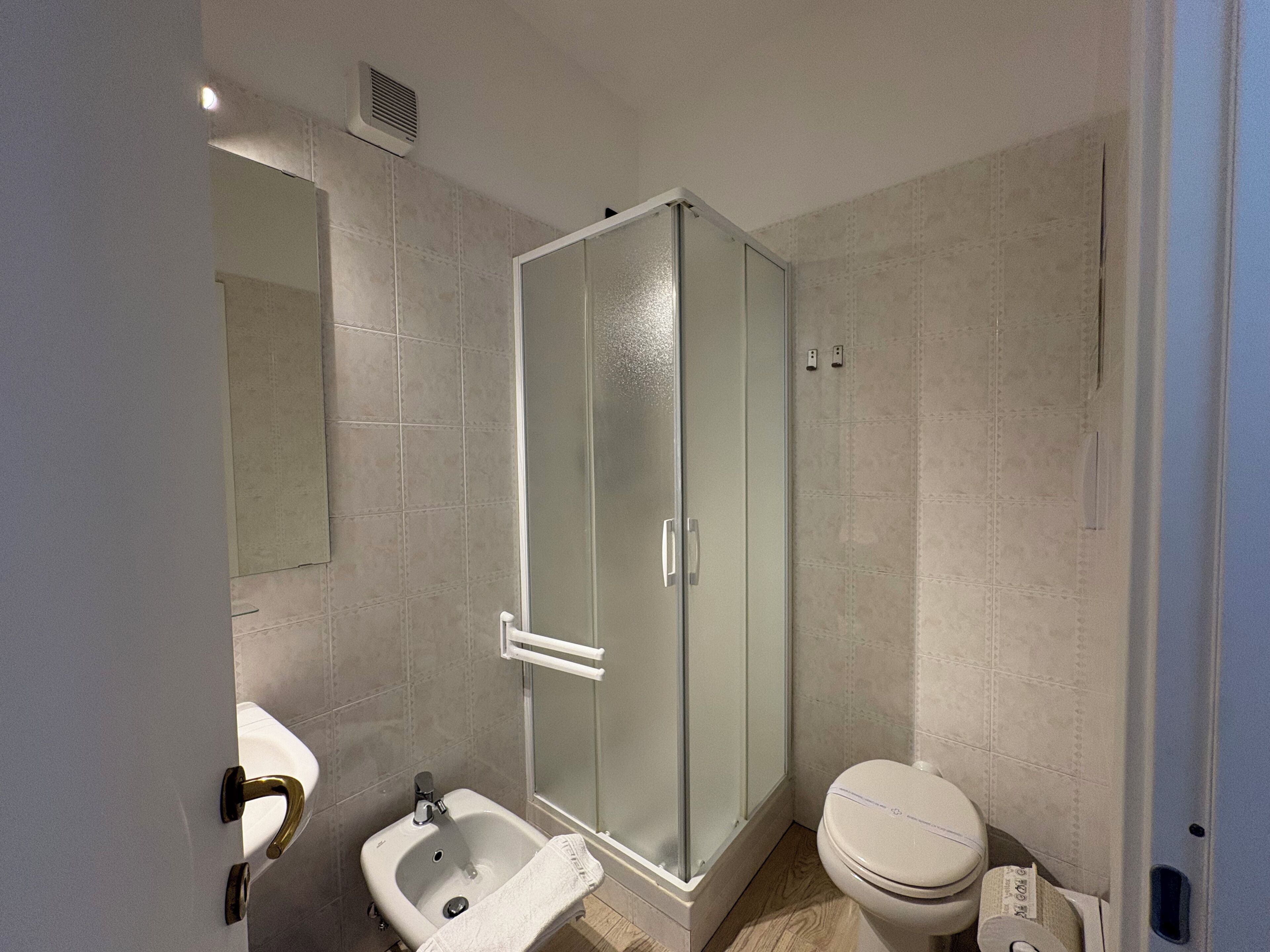 Een badkamer met een douchecabine van glas, een wastafel en een toilet.