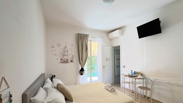 Un dormitorio con cama, escritorio, silla, televisión de pantalla plana y ventana con cortinas.