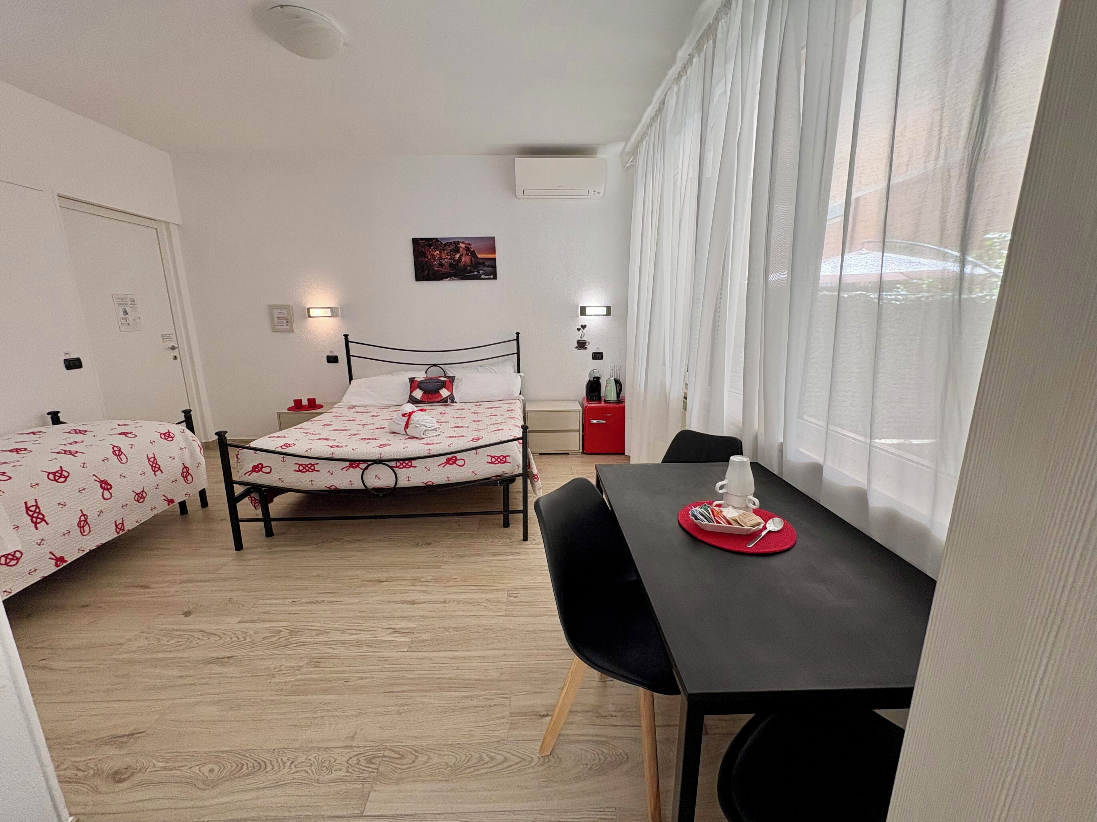 A bedroom with a bed, a bedside table, a chair, a desk, and a window with curtains.