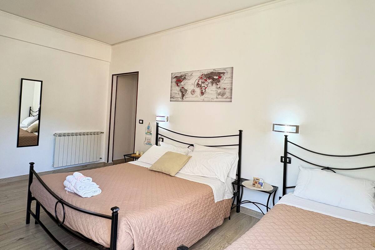 A bedroom with two beds, a radiator, a world map artwork, and a mirror.