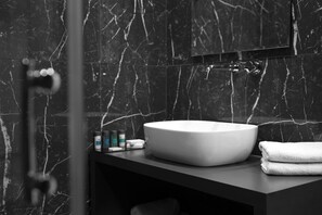 Une salle de bain avec un lavabo en marbre, une serviette et des articles de toilette posés sur le comptoir.