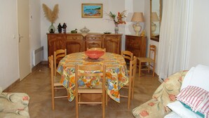 A dining area with a round table, chairs, a decorative vase, and a painting on the wall. - Gîte Calzolari in Corsica (Castifao)