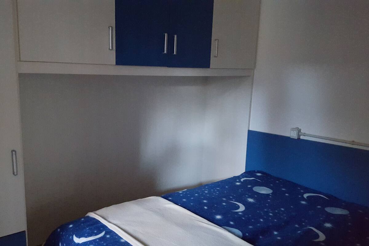 Een kleine kamer met een bed, een kledingkast en een nachtkastje.