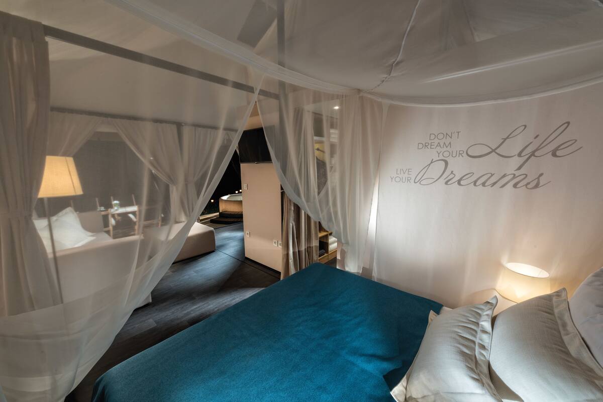 Een slaapkamer met een bed, een muur met motiverende tekst en een hemelbed.