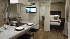 Une chambre d’hôtel moderne comprenant un coin repas, une télévision, un lit et un espace nuit séparé.