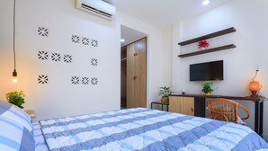 Un dormitorio con cama, escritorio, silla, televisor y paneles decorativos en la pared.