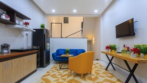 Una cocina compacta con electrodomésticos modernos, un sofá y una mesa de comedor con plantas en macetas.