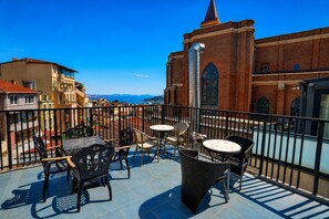A balcony with outdoor furniture, a view of a church, and a cityscape in the background. - Taksim Yazici Residence (Istanbul)