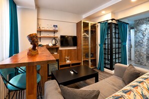 A modern living room with a wooden dining table, a sofa, a TV, and a glass cabinet. - Taksim Yazici Residence (Istanbul)