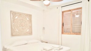 Ein Schlafzimmer mit einem Bett, einem Nachttisch, einer Wanddekoration und einem Fenster mit Jalousien.