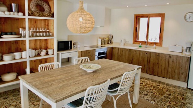 Eine moderne Küche mit weißen Schränken, einem Holztisch und einer Pendelleuchte.