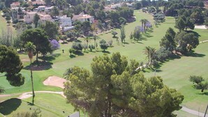 Ein Golfplatz mit Clubhaus, umgeben von Wohngebäuden und dichter Bepflanzung.