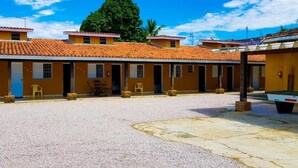 Una hilera de edificios amarillos con techos de tejas rojas, un patio de grava y una mesa de billar.