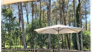 A wooden deck with a hot tub, lounge chairs, and an umbrella. - Au Clair Des Landes (Castets)