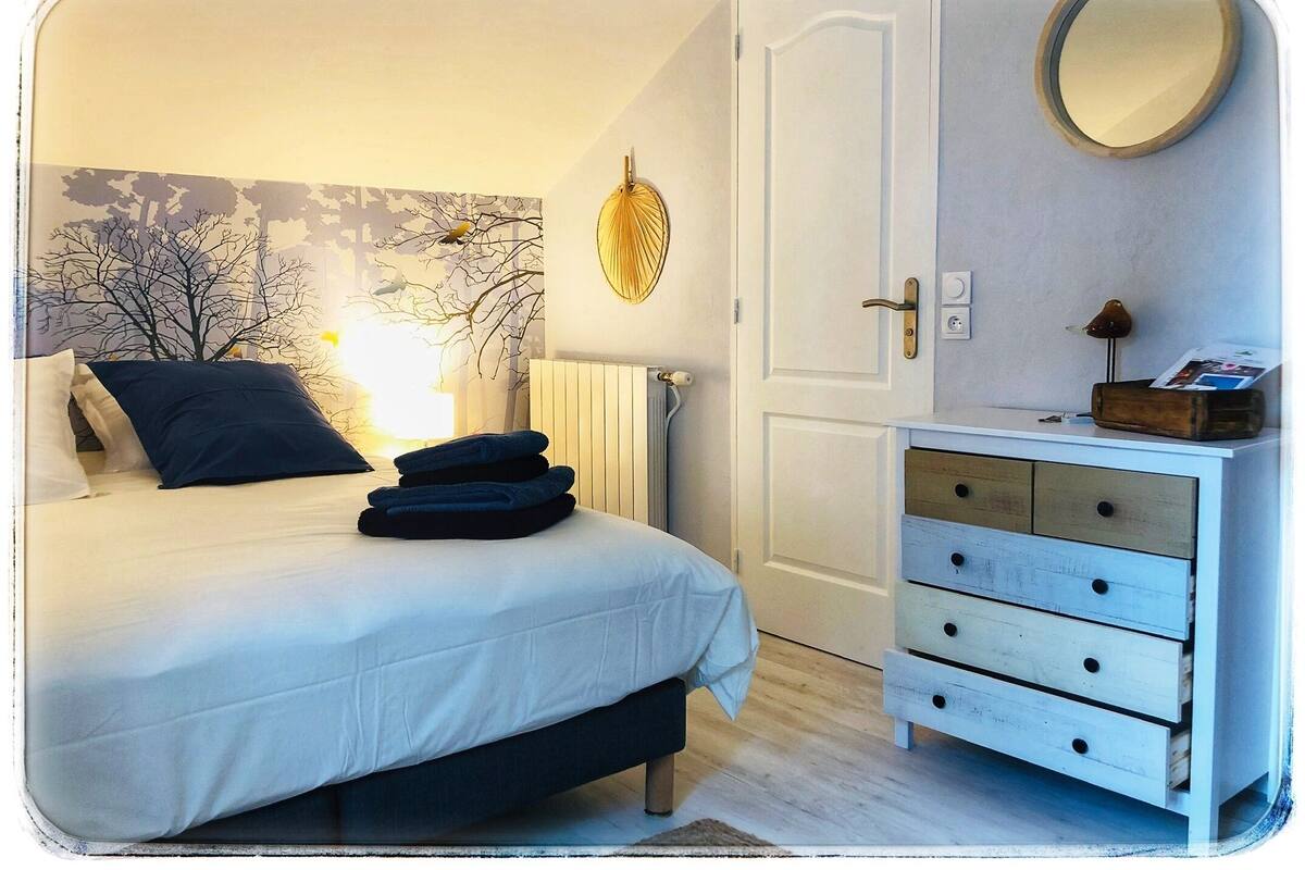 A bedroom with a bed, a dresser, a radiator, and a wall-mounted mirror.