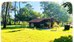 A small wooden cabin with a red roof, surrounded by a well-maintained lawn and trees. - Au Clair Des Landes (Castets)