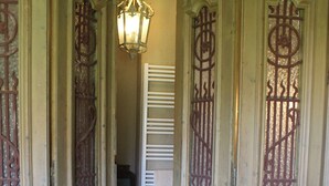 A wooden door with intricate metalwork, a hanging light fixture, and a potted plant on a small table.