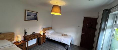 A hotel room with a bed, bedside table, lamp, and a window with curtains.