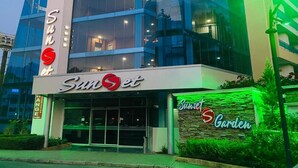 Un edificio moderno con una amplia fachada de vidrio y un letrero que dice "Sunset Garden".